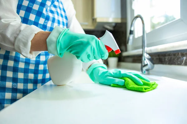 Unrecognizable woman cleaning kitchen counter with rag and spray cleaner