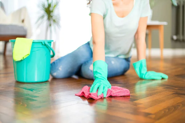 Young housewife with gloves cleaning the floor. Routine house chores concept