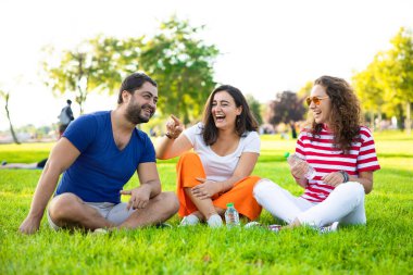 Üç güzel arkadaş parkta oturuyor, gülüyorlar ve harika vakit geçiriyorlar.