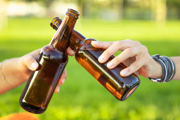 The hands holding bottles with beer and making cheers