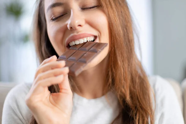 Веселая Молодая Женщина Ест Шоколад Дома — стоковое фото