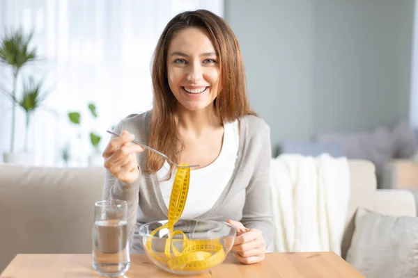 快乐漂亮的女人拿着叉子 带着尺寸尺坐在客厅里 健康饮食和饮食 — 图库照片