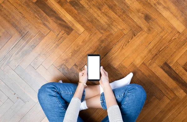 若い女性が自宅で床に座って携帯電話を使用しています — ストック写真