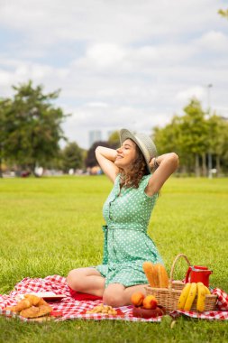 Güzel genç bir kadın güneşli bahar gününde piknik yapıyor.