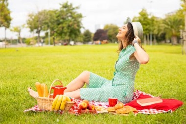 Güzel genç bir kadın güneşli bahar gününde piknik yapıyor.
