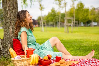 Güzel genç bir kadın güneşli bahar gününde piknik yapıyor.