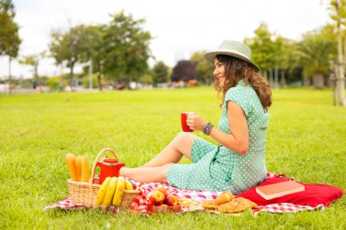 Güzel genç bir kadın güneşli bahar gününde piknik yapıyor.