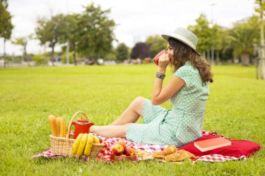 Genç bir kadın piknikte çay içiyor ve dinleniyor.