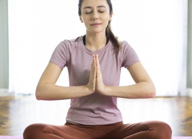 Genç bir kadın dua ediyor, meditasyon yapıyor, el ele tutuşuyor, evde dua ediyor.