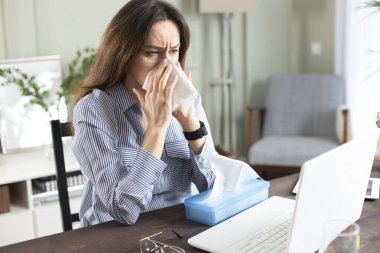 Freelancer hastası kadın hastalanmış, hasta ve evinde çalışırken kağıt mendile hapşırmış.