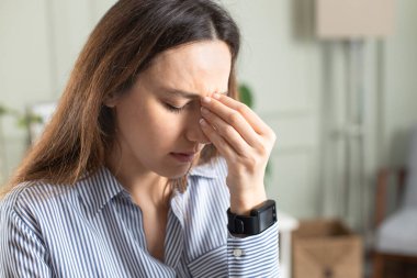 Evde baş ağrısı çeken serbest çalışan genç bir kadın.