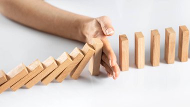 Kadının eli düşmeyi durdurdu. Tahta domino taşları beyaz katı zemini etkiliyor.