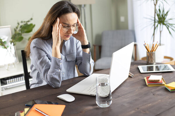 Стрессовая деловая женщина, работающая над ноутбуком в доме