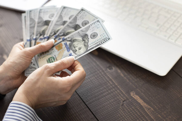 Неузнаваемая девушка, считающая доллар США на офисном столе