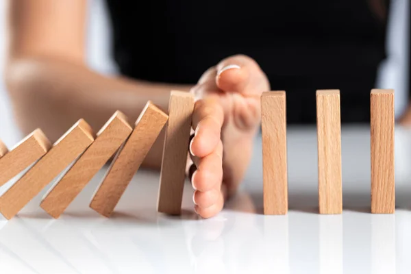 Frauenhand Stoppt Fallende Hölzerne Dominosteine Auf Weißem Festen Boden — Stockfoto