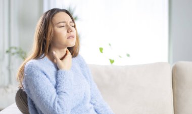 Genç bir kadın ağrılı boynuna dokunuyor. Grip, soğuk algınlığı ve enfeksiyon yüzünden boğazı ağrıyor.