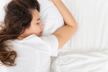 Genç bir kadın yatağında uyuyor.