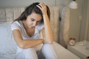 Üzgün depresif kadın uykusuzluk çekiyor, yatakta oturuyor ve kafasına dokunuyor, uyku bozukluğu ya da stres konsepti