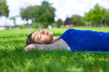 Genç bayan çimenlere uzanıp huzur içinde dinleniyor.