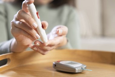 Kadın elleri kan şekeri seviyesini ölçmek için parmak üzerine mızrak kullanıyor. İlaç, diyabet, glisemi ve sağlık konsepti.