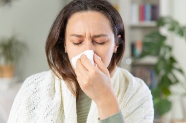 Genç bir kadının evdeki bir mendille burnunu silmesi.