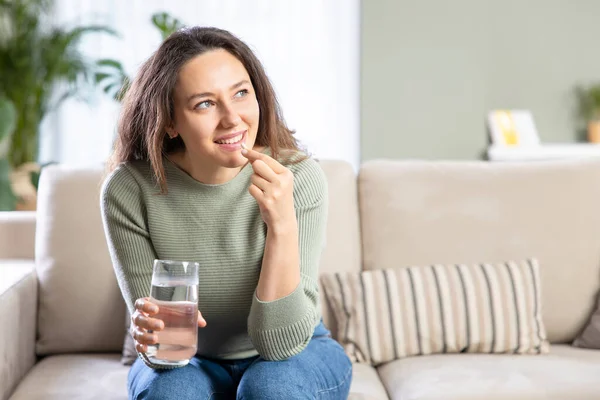 Lächelnde Junge Frau Lindert Krankheitssymptome Unter Einnahme Einer Schmerztablette Sitzend — Stockfoto