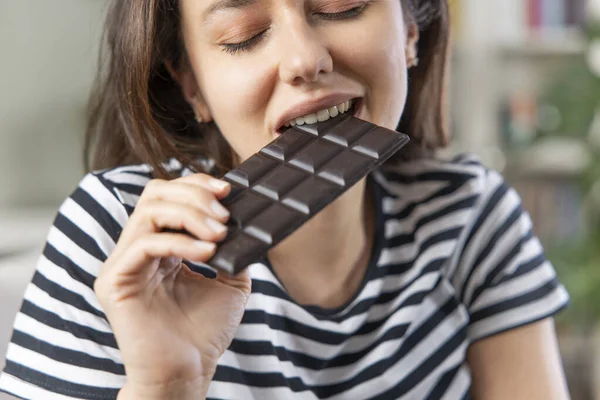 Junge Frau Isst Schokoriegel Wohnzimmer — Stockfoto