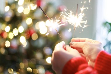 Noel ağacında yanan maytap tutan kadın. Yeni yıl kutlaması 