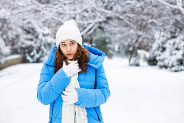 Şehirde karlı bir kış gününde mavi kışlık elbiseli genç bir kadın.