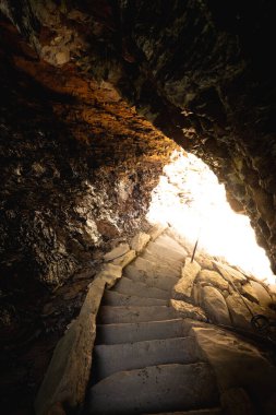 Merdivenlerden aşağı, mağara kemerlerinden güneşe doğru inen izler.