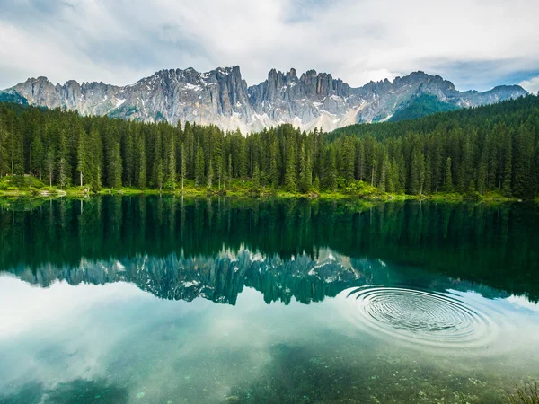 Latemar bergketen en bossen weerspiegeld in lake Carezza (Karersee) bij zonsondergang in een bewolkte dag, Dolomieten, Italië — Stockfoto