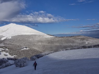 Uzun yürüyüşe çıkan kimse dağlarda kar, mavi gökyüzü bulutlu, Apennines, Umbria, İtalya