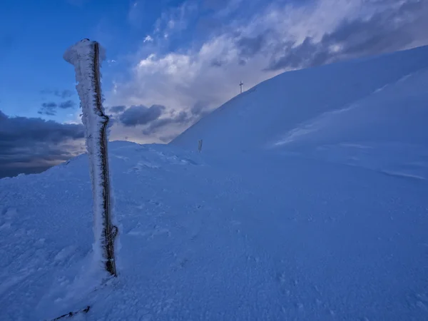 Hiker reaching the frozen summit cross of mount Catria in winter, Apennines, Italy — Stock Photo, Image