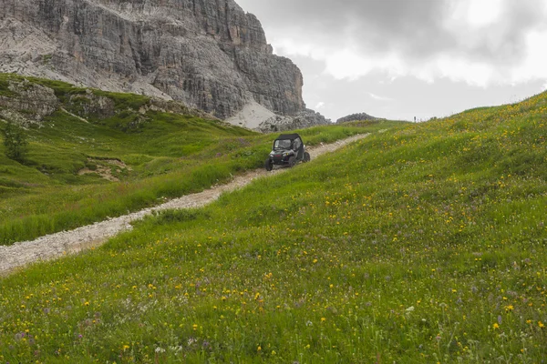 Dune buggy su un sentiero di montagna tra i prati verdi, Dolomiti, Veneto, Italia — Foto Stock