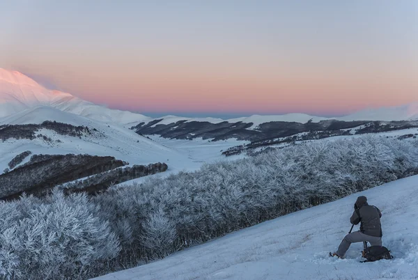 Fotograf som arbetar i bergen på vintern vid solnedgången med s — Stockfoto