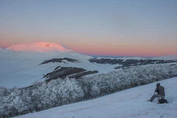 Fotógrafo trabajando en las montañas en invierno al atardecer con s — Foto de Stock