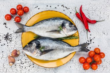 Sarı plaka ve sebze beyaz masa üzerinde ham dorado balık.