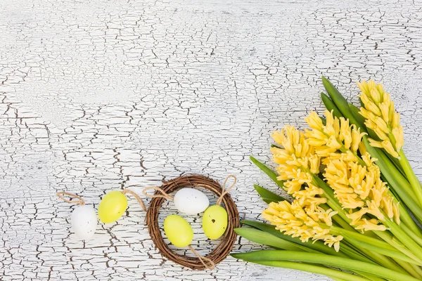 Osterhintergrund mit gelben Blumen und dekorativen Eiern in kleinem Nest — Stockfoto