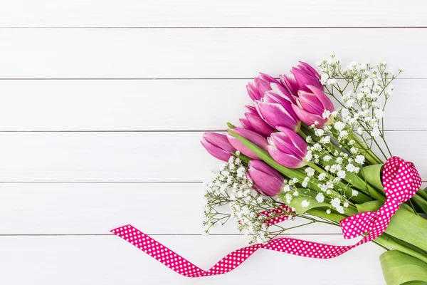 Аромат ярко-розовых тюльпанов и гипсофилы украшен лентой на белом деревянном фоне — стоковое фото