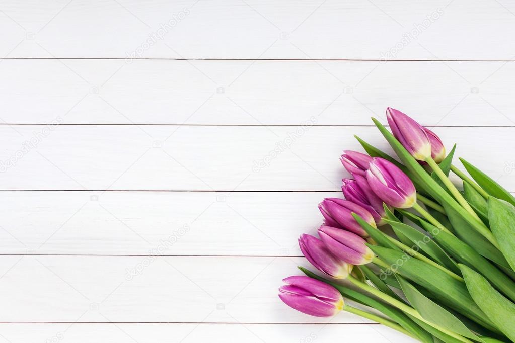 Bouquet of pink tulips on white wooden background. Top view