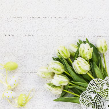 Easter eggs and white tulips on vintage tablecloth. Holiday background