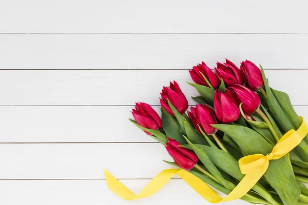 Bright red tulips decorated with yellow ribbon. Copy space — Stock Photo, Image