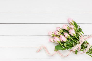 Beyaz ahşap arka plan üzerinde dantel ile süslenmiş pembe gül buketi. Üstte görüntü