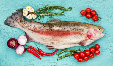 Mavi ahşap masada sebze ile taze alabalık balık. Üstte görüntü