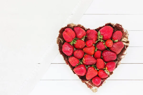 Fraises fraîches dans une assiette sur une table en bois blanc. Vue du dessus, espace de copie — Photo