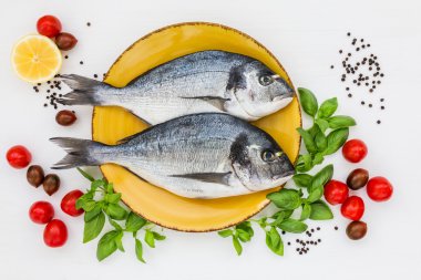 Beyaz ahşap masa üzerinde sarı plaka üzerinde taze dorado balık. Üstten Görünüm