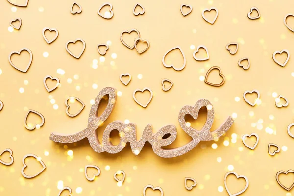 Conceito de celebração do Dia dos Namorados. Corações de madeira e a palavra AMOR em um fundo amarelo. — Fotografia de Stock