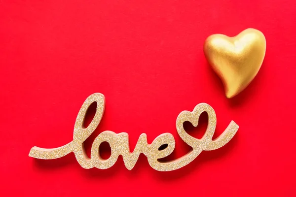 Coração dourado e palavra AMOR em um fundo vermelho. Conceito do Dia dos Namorados. — Fotografia de Stock