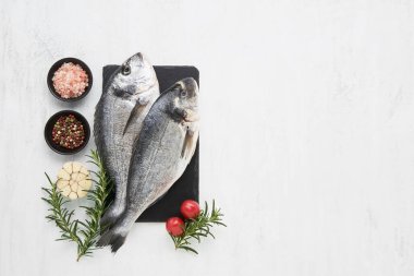 Baharatlı çiğ dorado balığı beyaz arka planda kesme tahtasında. Akdeniz ürünleri konsepti. Üst görünüm, metin için boşluk kopyala