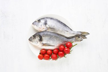 Arka planda beyaz tabakta çiğ dorado balığı. Akdeniz ürünleri konsepti Üst görünüm, metin için kopyalama alanı